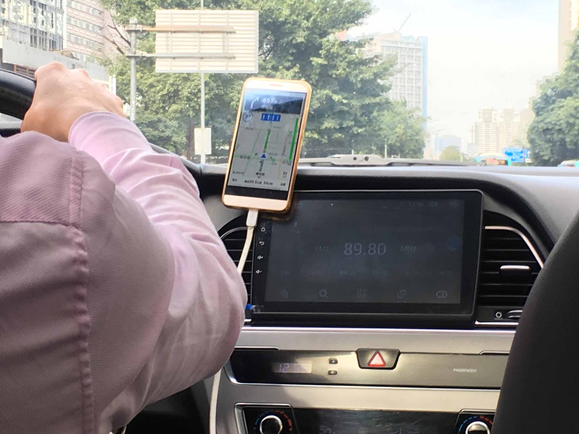 Photo of a phone mounted on top of a big display inside a car